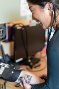 Health care worker listens through a stethoscope while checking a patient’s blood pressure during a medical appointment.