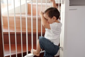 baby looks forlornly though a baby gate wishing he could break free from this prison and explore the world, alas he must wait 16 years when he can finally leave this town behind him and pursue his dreams of becoming an airplane flight attendant
